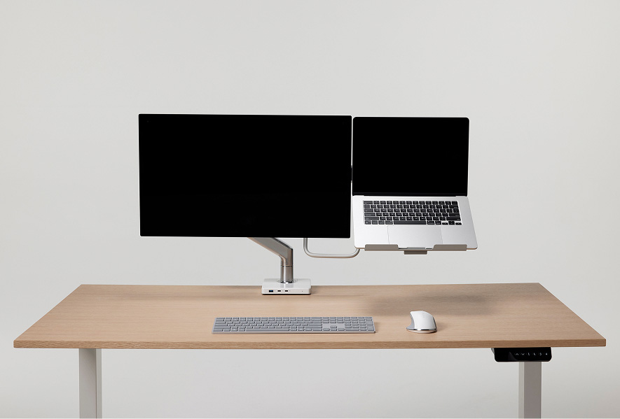 Combinaison d’un bras pour moniteur et d’un support pour ordinateur portable sur un poste de travail